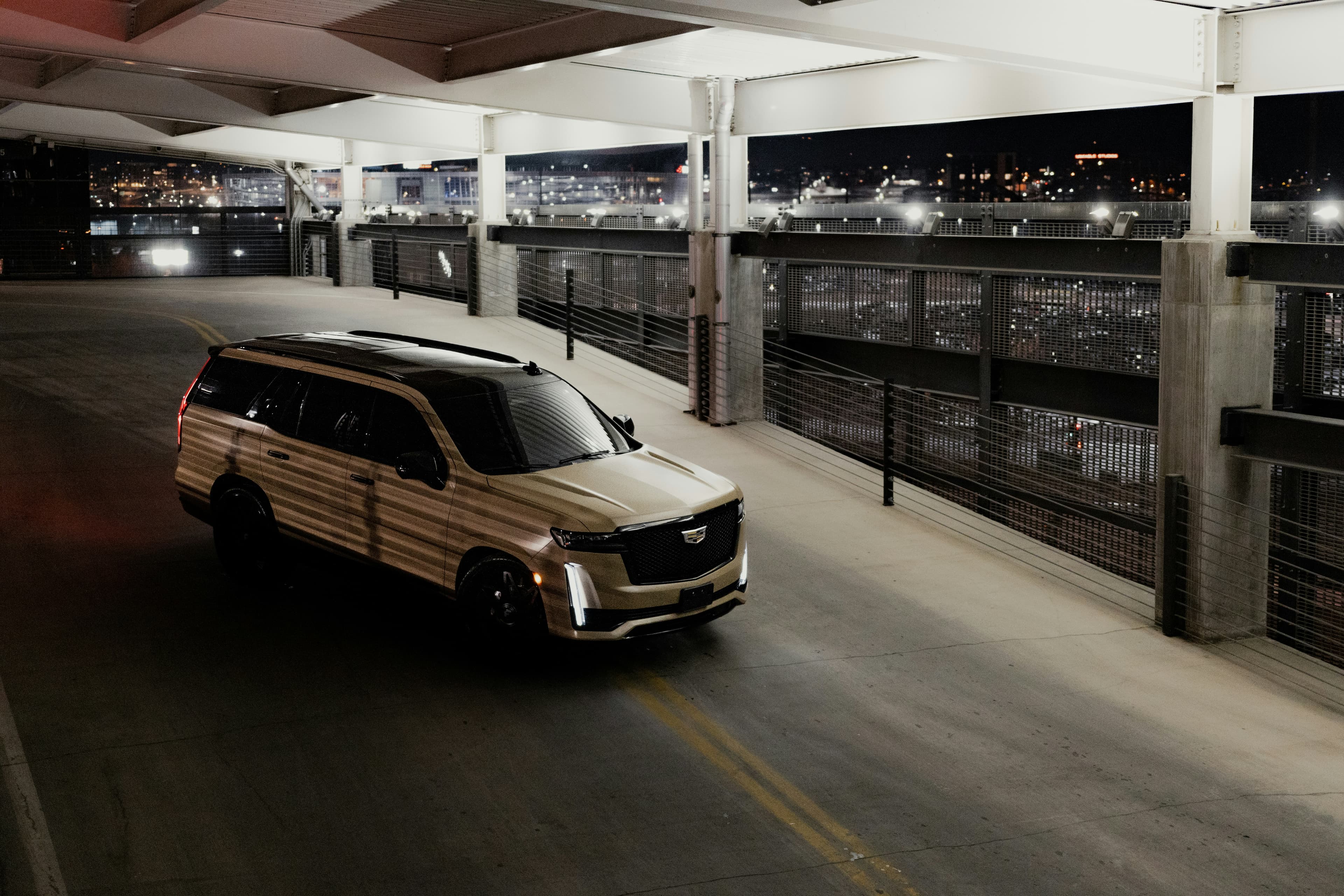 Black Cadillac Escalade SUV parked on the Las Vegas Strip at night with neon lights reflecting